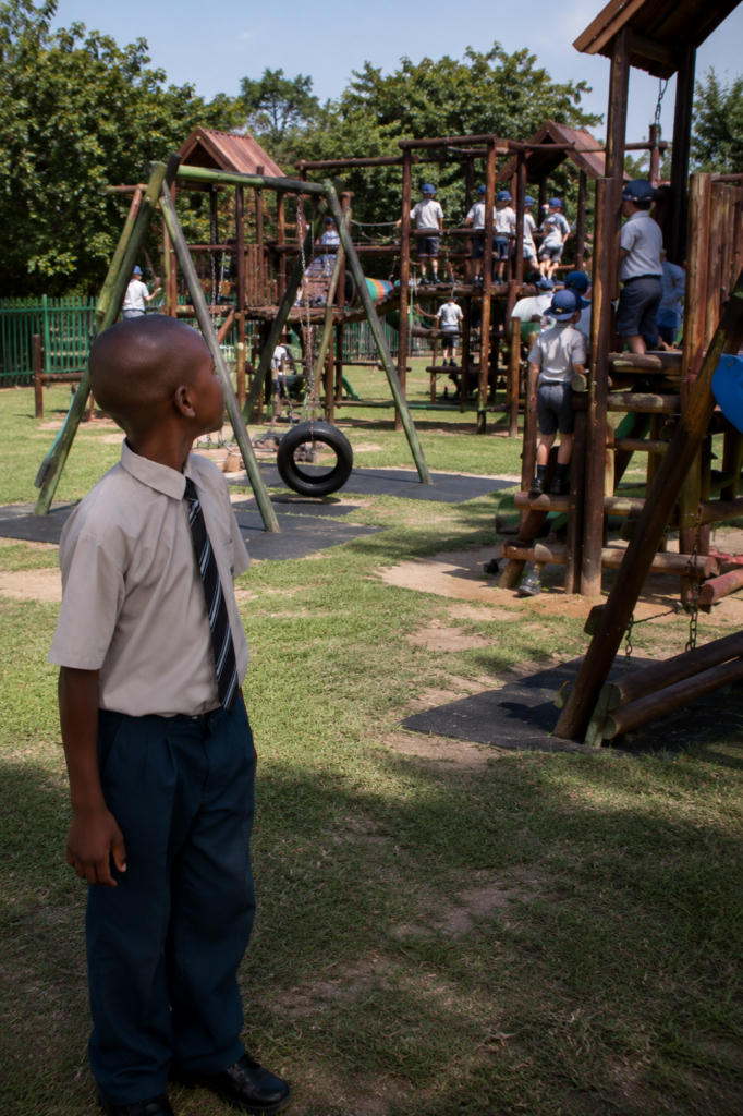 Living Between Worlds showing young Mpumelelo discovering a private school playground for the first time in Orkney, South Africa